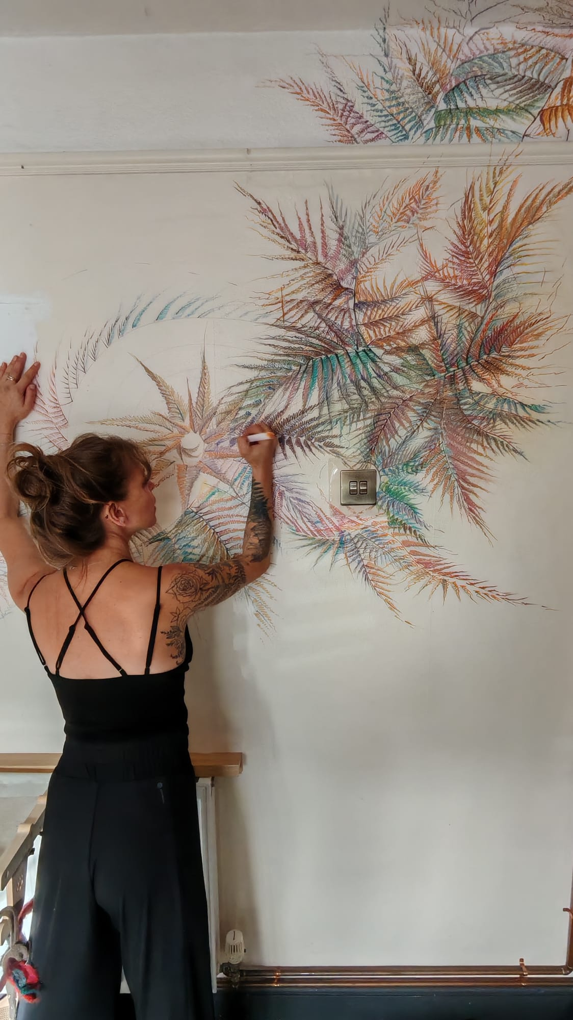 Anneka Reay drawing an intricate botanical mural